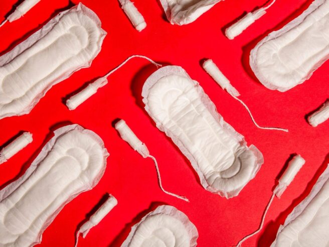 age Description: Pads and tampons are scattered across a red background.