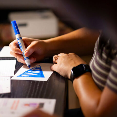 Person coloring in a "Vote" postcard.